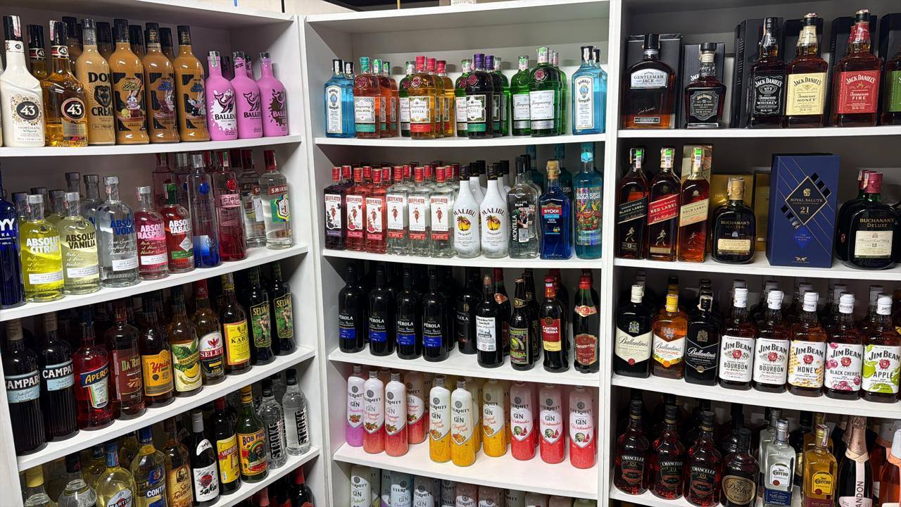 Prateleiras da adega com gins, vodkas, whiskies, licores e vinhos